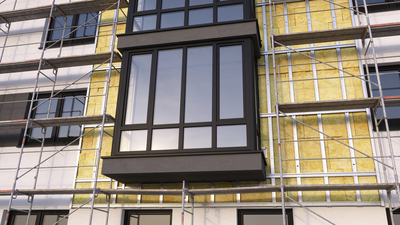 Scaffolding surrounding a modern residential building undergoing thermal insulation and exterior renovation.
